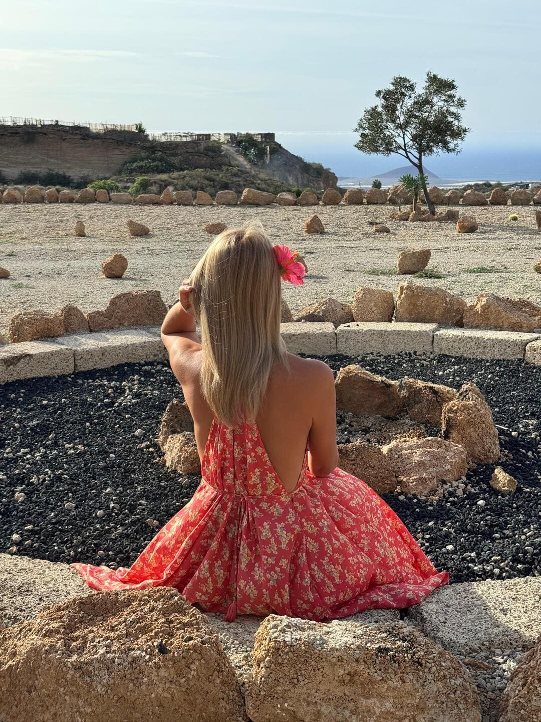 Femeie privind oceanul din Tenerife, într-o rochie florală roșie